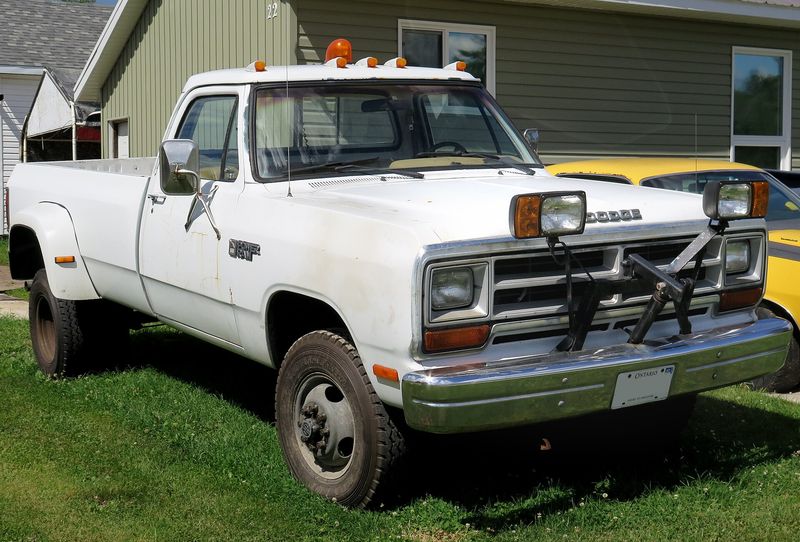 White 1988 Dodge Power Ram W350 dually with a plow mount and roof lights